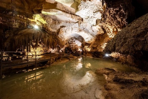 Stalactites and stalagmites, small underground lake, rock formations in a stalactite cave, Grotta