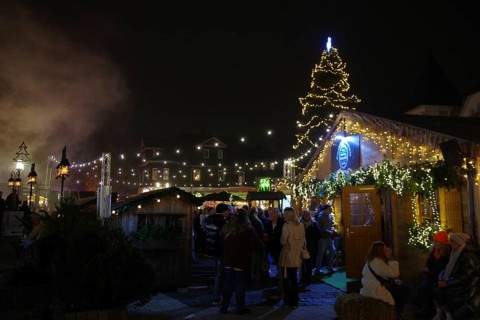 A lively Christmas market at night with illuminated wooden stalls and lots of visitors, Winterberg,