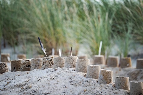 Sandcastle on the beach, detailed view of a sand castle with small towers and dug in the sand,