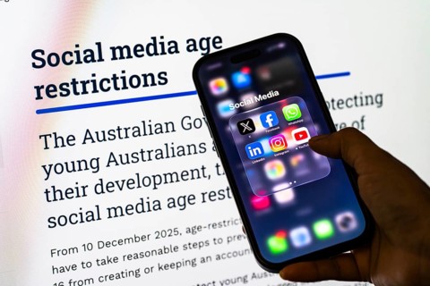 In this photo illustration, a person holds a smartphone displaying popular social media apps in
