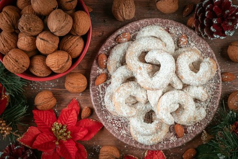 Vanilla croissants on a plate next to walnuts and Christmas decoration