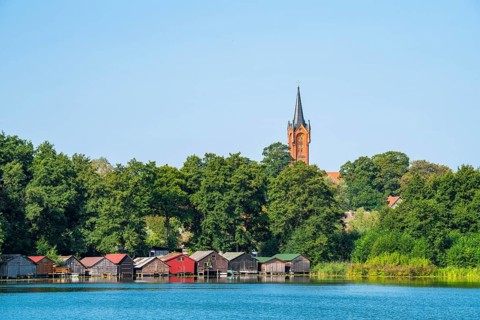 View across the Haussee to the town church and colorful boathouses on stilts, Feldberg, Feldberg