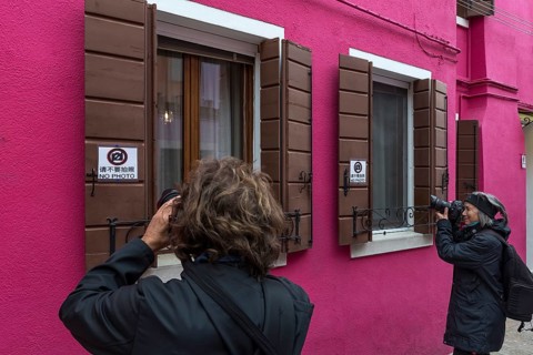 Tourists take pictures of a house in Burano, Venice, Italy