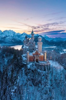 Neuschwanstein Castle in winter landscape at dusk with mountain backdrop, Schwangau near Füssen,