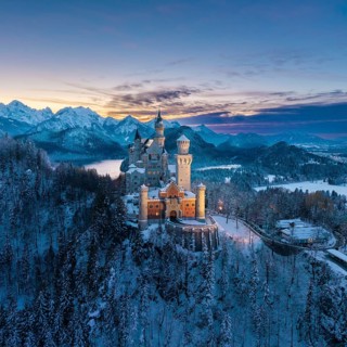Snowy Neuschwanstein Castle surrounded by alpine mountains at dusk, Schwangau near Füssen,