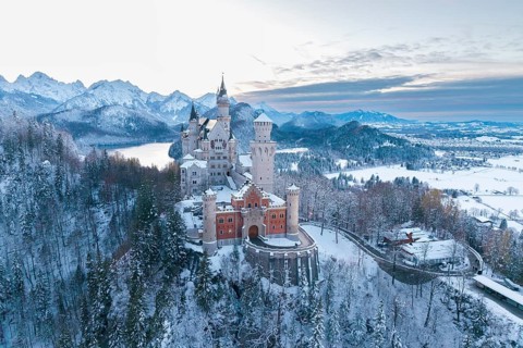 Snowy Neuschwanstein Castle at dusk, surrounded by mountains and soft winter light, Schwangau near