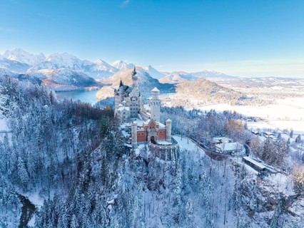 Winter landscape with Neuschwanstein Castle, surrounded by snow-covered forests and mountains,