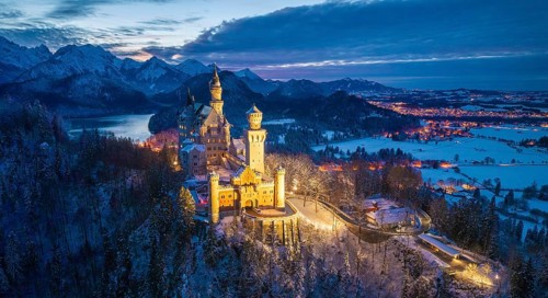 Panoramic view of Neuschwanstein Castle in snowy mountain landscape at dusk, night view, Schwangau