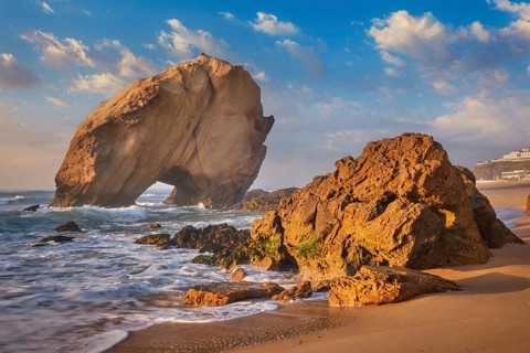 Penedo do Guincho, a large boulder rock arch at Praia da Santa Cruz, Portugal, with ocean waves and