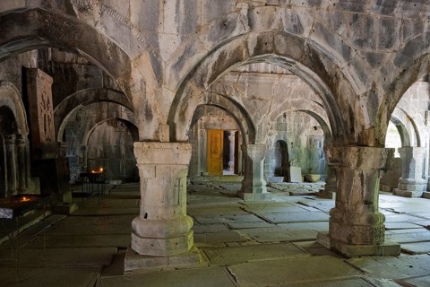 Ancient room with stone arches and yellow lighting creates a quiet, historic atmosphere, Sanahin