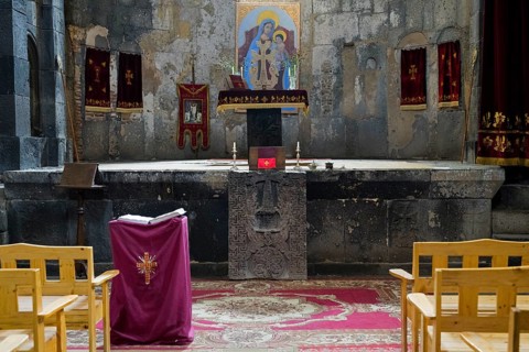 Small altar in a church with icon surrounded by burgundy fabric and wooden furniture, Sanahin