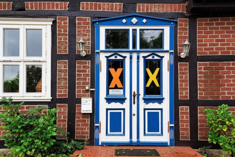 Characteristic half-timbered house, façade detail, blue white door, yellow X symbol, resistance