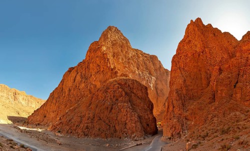 Dramatic red rocks in a sunny desert landscape with clear sky, Morocco, Todra Gorge