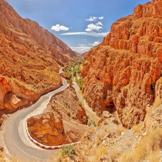 Serpentine road through steep, red rock walls under blue sky, Morocco, Dade Valley, panorama