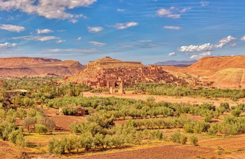 Historic clay buildings in an oasis surrounded by desert landscape, Morocco, Ait Ben Haddou,
