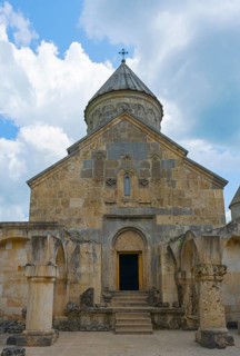 Front view of a stone church with distinctive entrance and tower in front of sky, Haghartsin