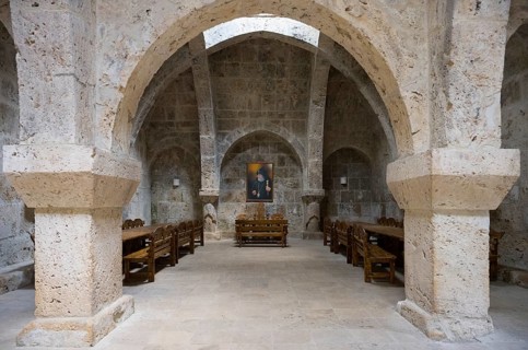 Stone vault with wooden furniture and paintings on the wall, sparse interior, refectory interior,