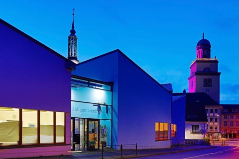 The Johanniszentrum with the top of St. John's Church and the Town Hall Tower in the evening,