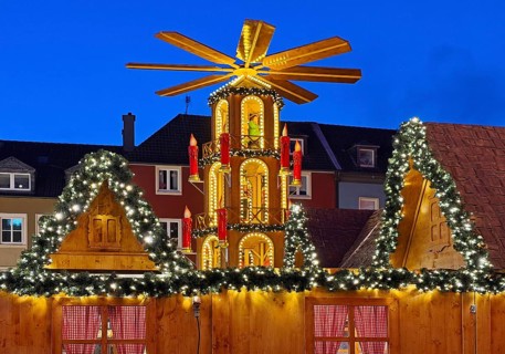 The Christmas market with the mulled wine pyramid in front of apartment buildings in the evening,