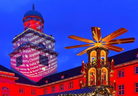 The Christmas market with the mulled wine pyramid and the illuminated town hall in the evening,