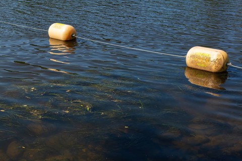 String of yellow cautionary navigation buoys on river water surface serving to warn, signal or
