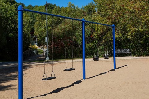 Swings installed in sandy ground in kids playground in city park in late summer, Parc du