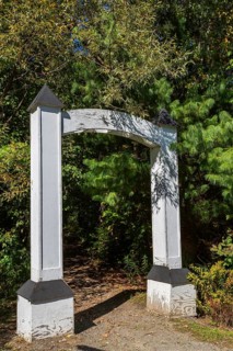 White painted wooden portal gate at start of hiking trail in public nature park in late summer,