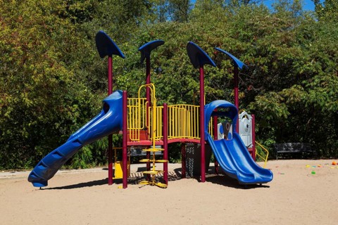 Kids playground equipment with slides, climbers and monkey bars installed in sandy ground in city