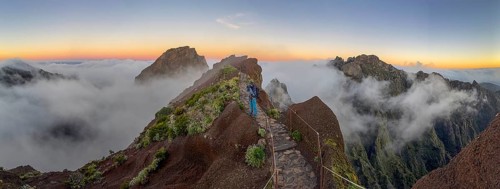 Photographer photographs sunrise at Pico do Arieiro, clouds of fog sweeping over mountain peaks,