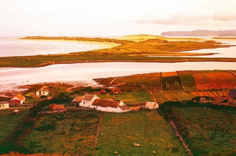 View over thatched farmhouse buildings to Magheraroarty Beach, Meenlaragh, County Donegal, Ireland