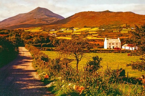 Farmland and rural landscape country road leading towards Derryveagh Mountains mountain range,