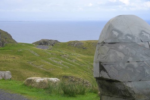Stone monument with animal representations in the background Eire sign, on the way to the Slieve