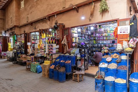 A colorful market stand full of spices, genes and products with a retailer inside a small shop,