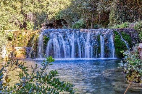 Fascinating waterfall flowing over green moss rocks into a natural basin, El Kelaa wild stream in