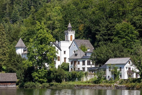 A, Hallstatt, A castle with towers and surrounding buildings on the lake, surrounded by forest,
