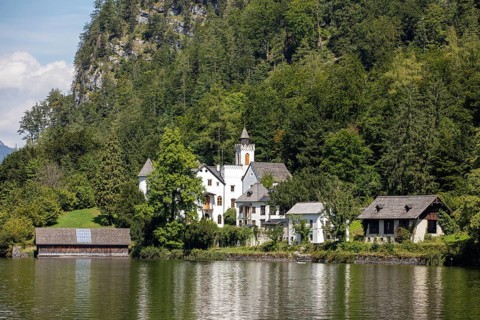 A, Hallstatt, An estate with several buildings on the shores of a lake, surrounded by trees,