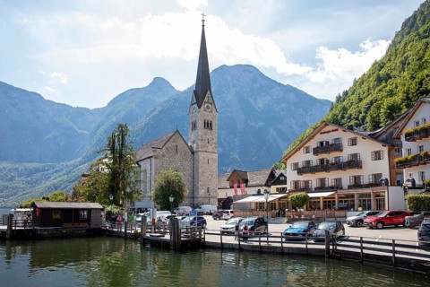 A, Hallstatt, church next to a lake in front of impressive mountains and clouds, quiet scenery,