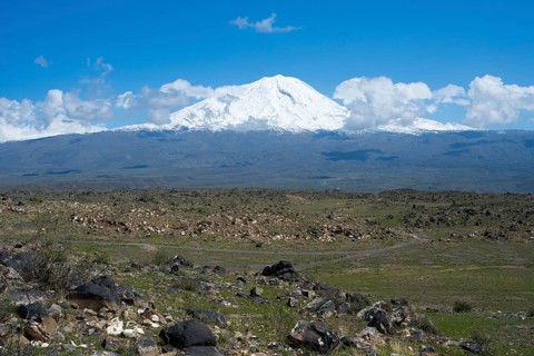 Peaceful landscape with snow-covered mountain and rocky plains under blue sky, landscape near