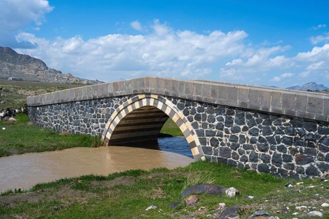 Stone bridge over a river in a green landscape under blue sky, bridge near Cevirme, Dogubayazit,