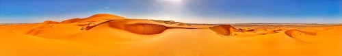 Panoramic view of vast orange sand dunes under bright skies, Sahara, Morocco