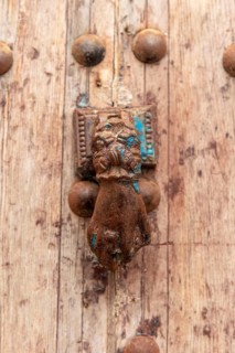 Old door knocker in the shape of a hand on a weathered wooden background