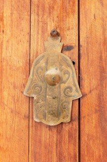 Ornamental brass handle in the shape of a hand on wooden door