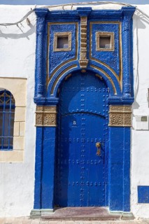 Blue, ornately decorated door in a white wall