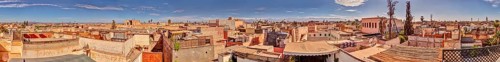 Panoramic view of the rooftops of Marrakech in Morocco under a blue sky with some clouds