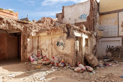 Dilapidated building with graffiti and trash in a deserted area, earthquake