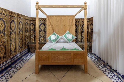 Cozy bedroom with traditional wooden canopy bed and ornate wall decorations, Bahia Palace in
