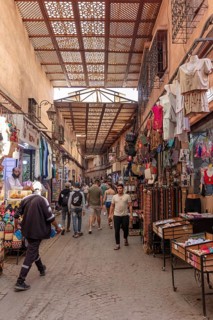 Covered market street with lots of people and colorful clothing stores