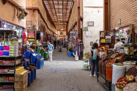 Lively, covered market street with various stalls and people shopping