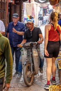 Lively Moroccan street with passers-by, motorcyclists and a historic atmosphere