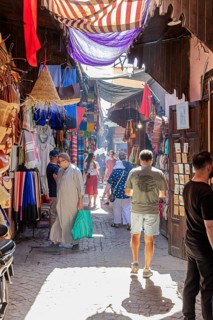 Colourful market with fabrics and lamps, full of people and lively hustle and bustle